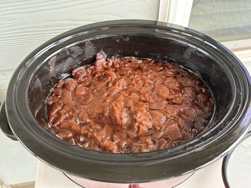 apples cooking down in a black crock pot