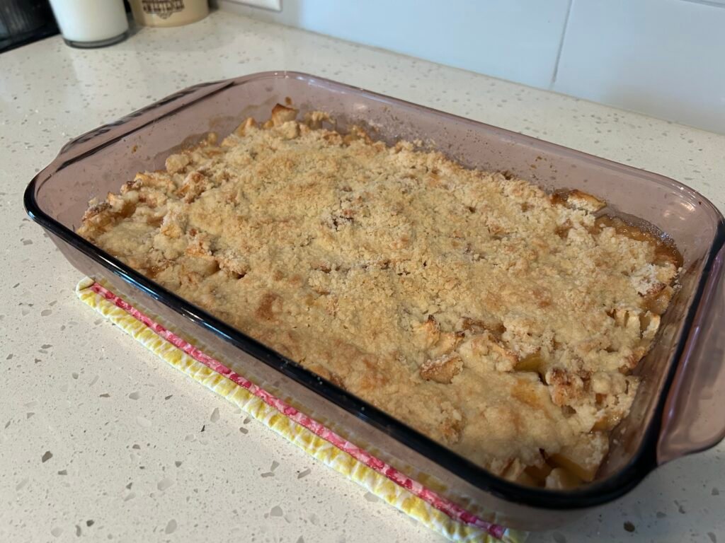 Baked apple crisp in a 9x13 baking dish cooling on a white counter.