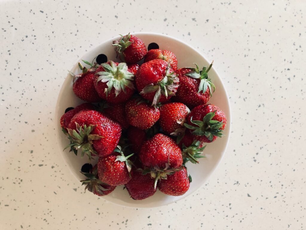 Cream bowl filled with ripe strawberries sitting on a white counter
