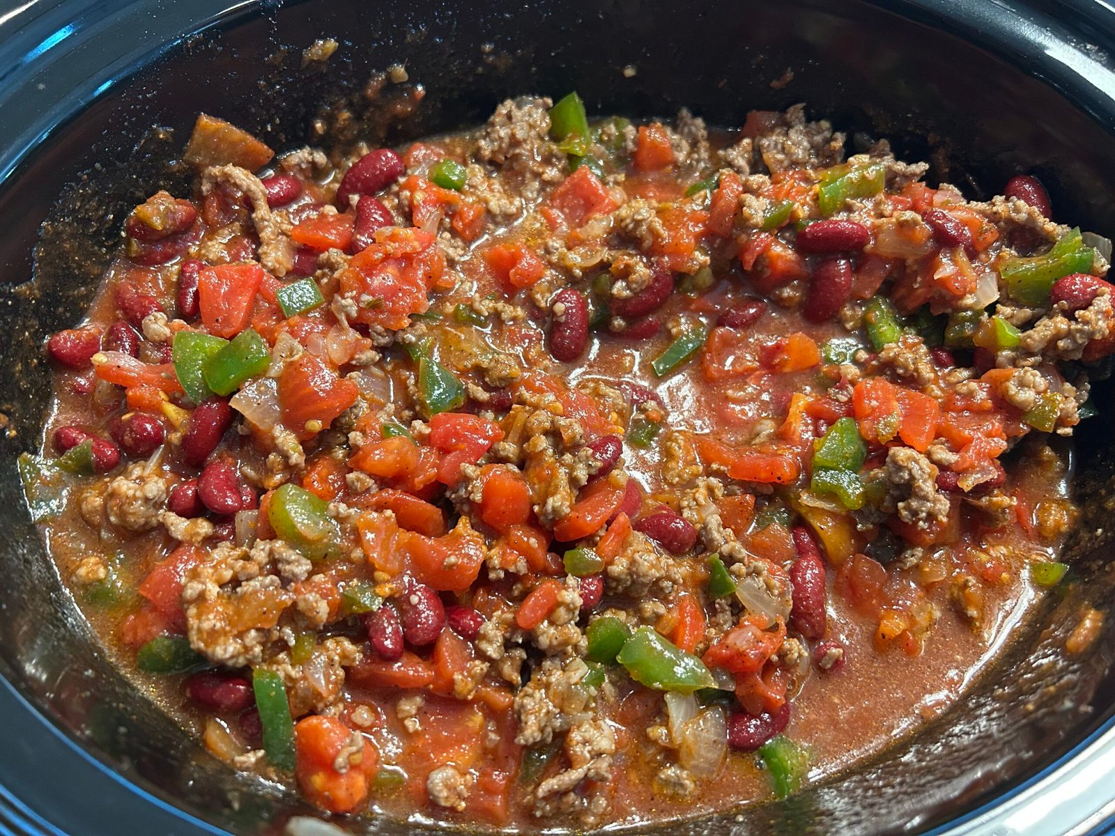 Crock-pot filled with ingredients to make a homestead chili recipe.