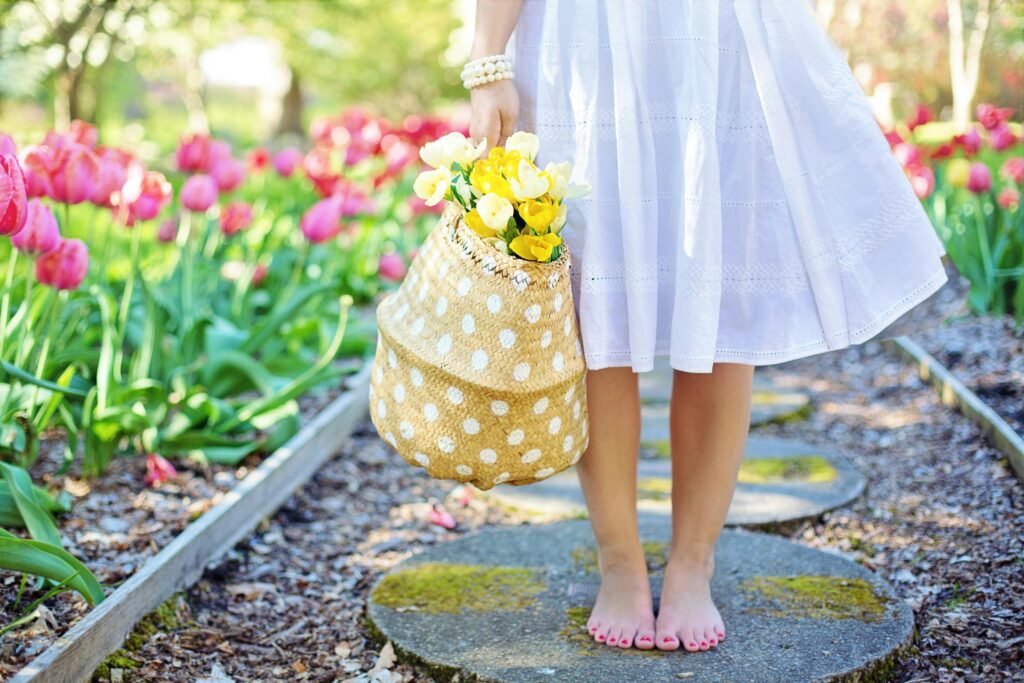 Girl in a white sundress standing on a garden path near tulips
