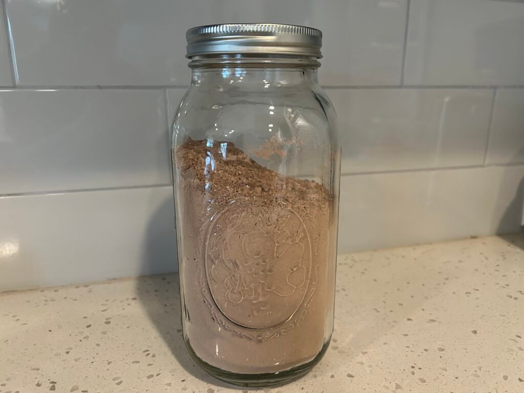 Half gallon mason jar filled with hot cocoa mix on white counter.