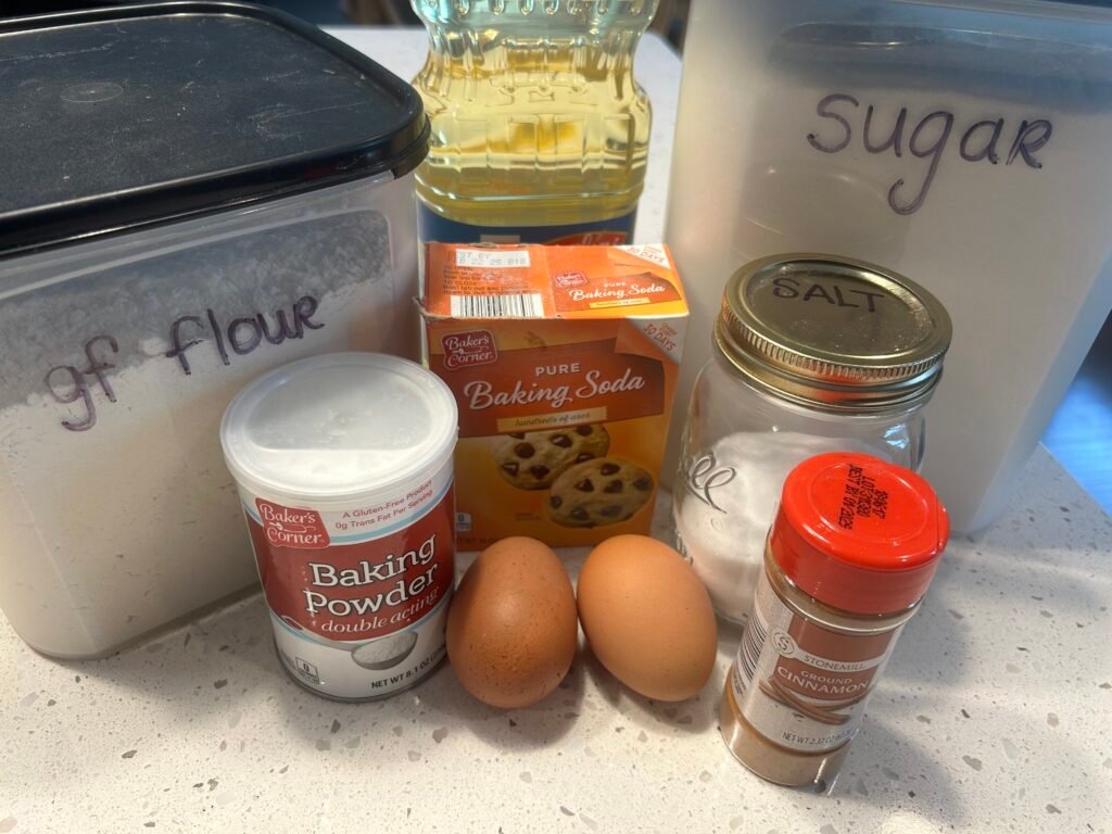Arranged ingredients to make a zucchini cake sitting on a white counter.
