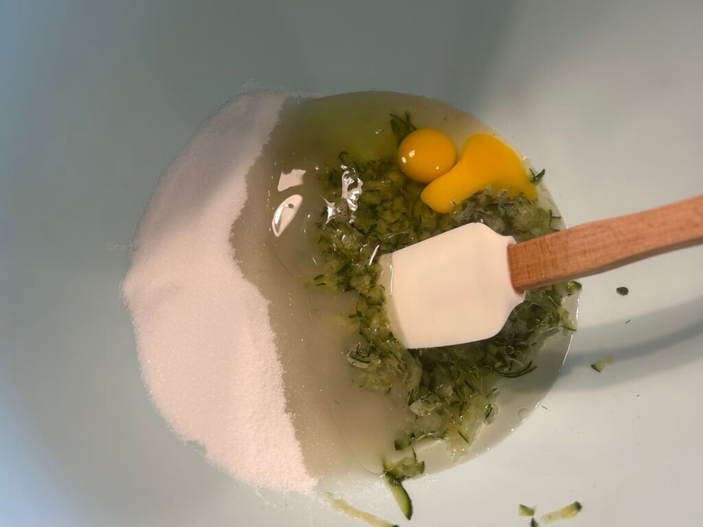 wet ingredients of eggs, zucchini, oil, and sugar in a blue bowl