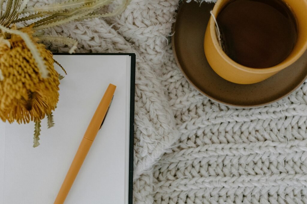Open journal to write simple living tips along with a cup of tea and a yellow flower