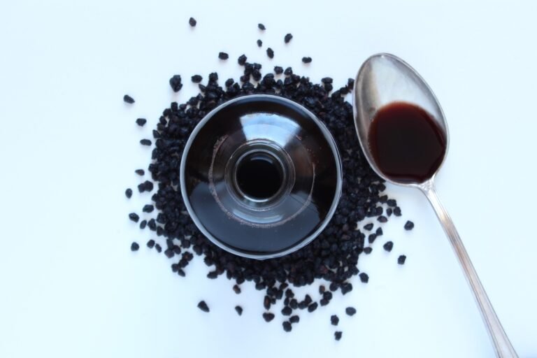 Bottle of elderberry syrup, berries and spoon