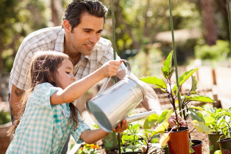 Girl with father using watering can in community garden