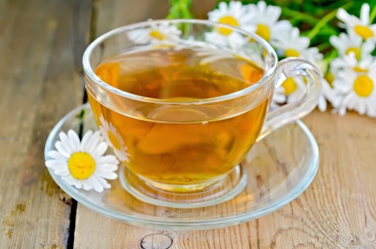 Herbal chamomile tea in a glass cup on a board