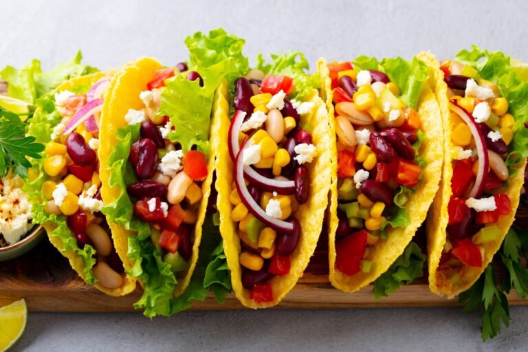 Taco with mixed vegetables, beans on cutting board. Grey background. Close up.